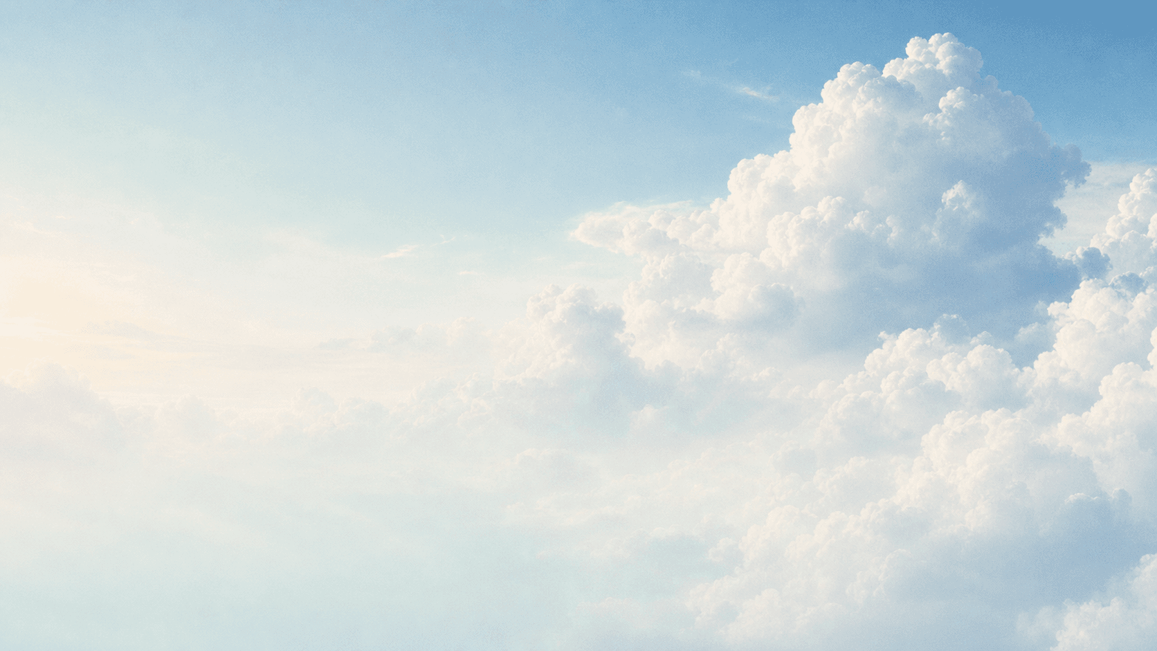 Sunlit white clouds moving through a calm pale blue sky