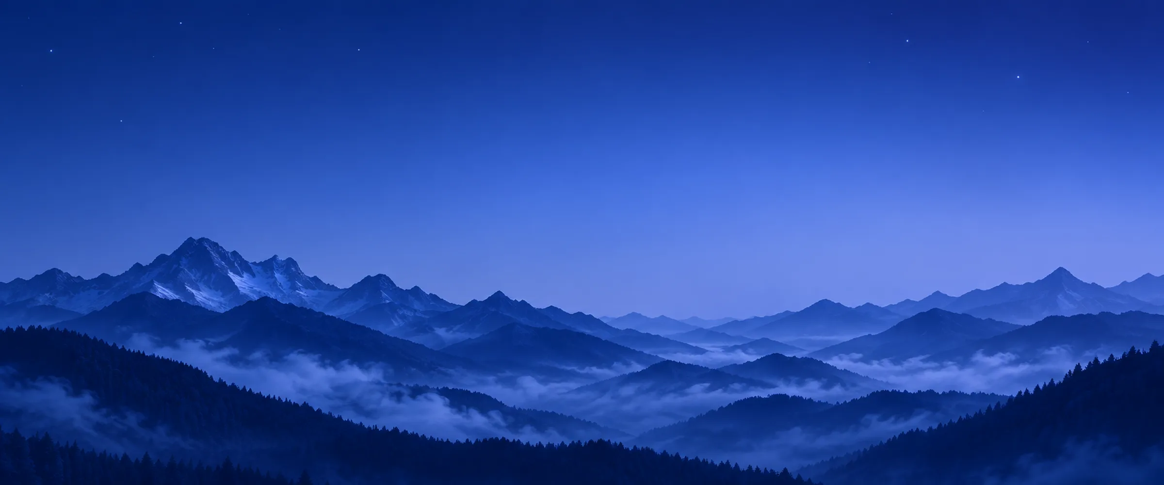 Cool blue hour over layered navy mountain silhouettes with low fog and a few first stars.