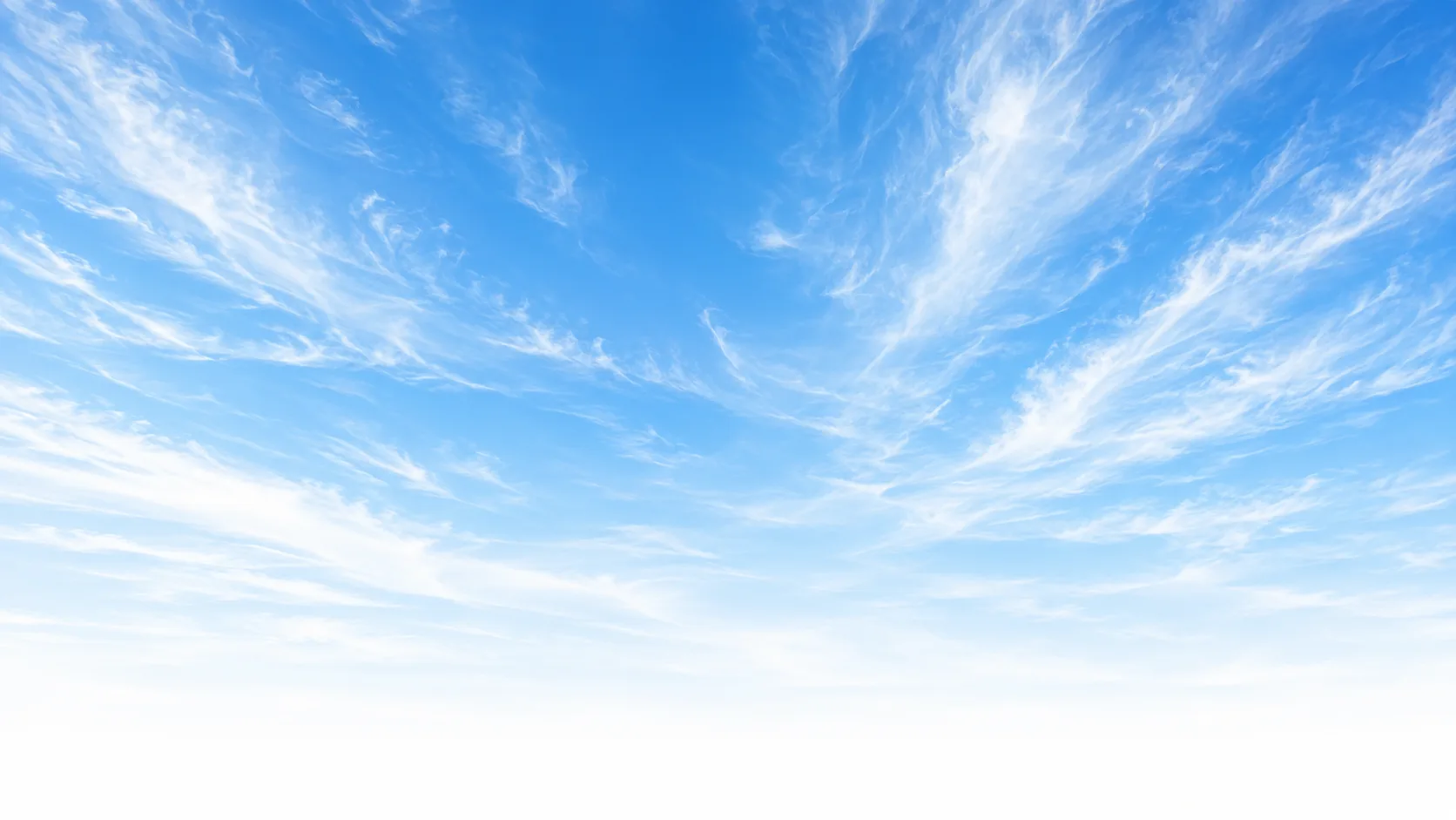 A cool white-blue sky crossed by high, thin, evenly spaced clouds, fading to white.